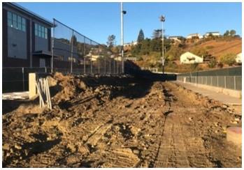 A neatly raked/tractored section of dirt that shows signs of previously holding concrete.